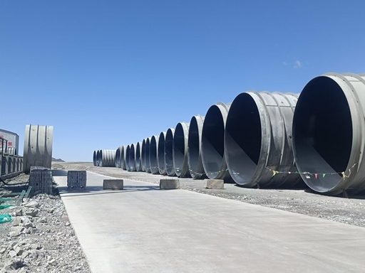 Large-diameter steel penstock sections arranged in an outdoor yard