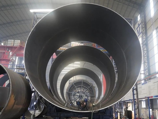 Large-diameter steel penstock sections in a fabrication workshop